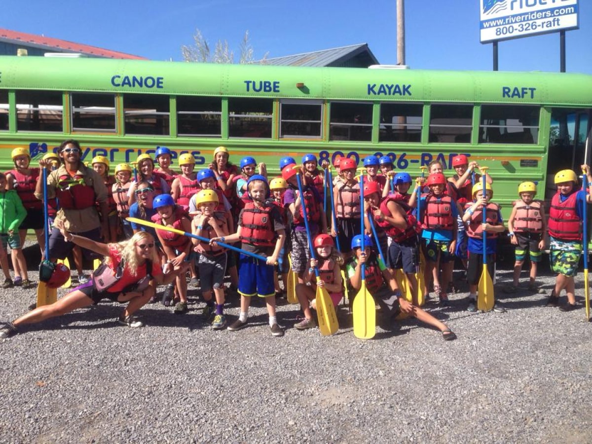 group of kids holding paddles in front of the bus at the Outdoor Adventure Camp