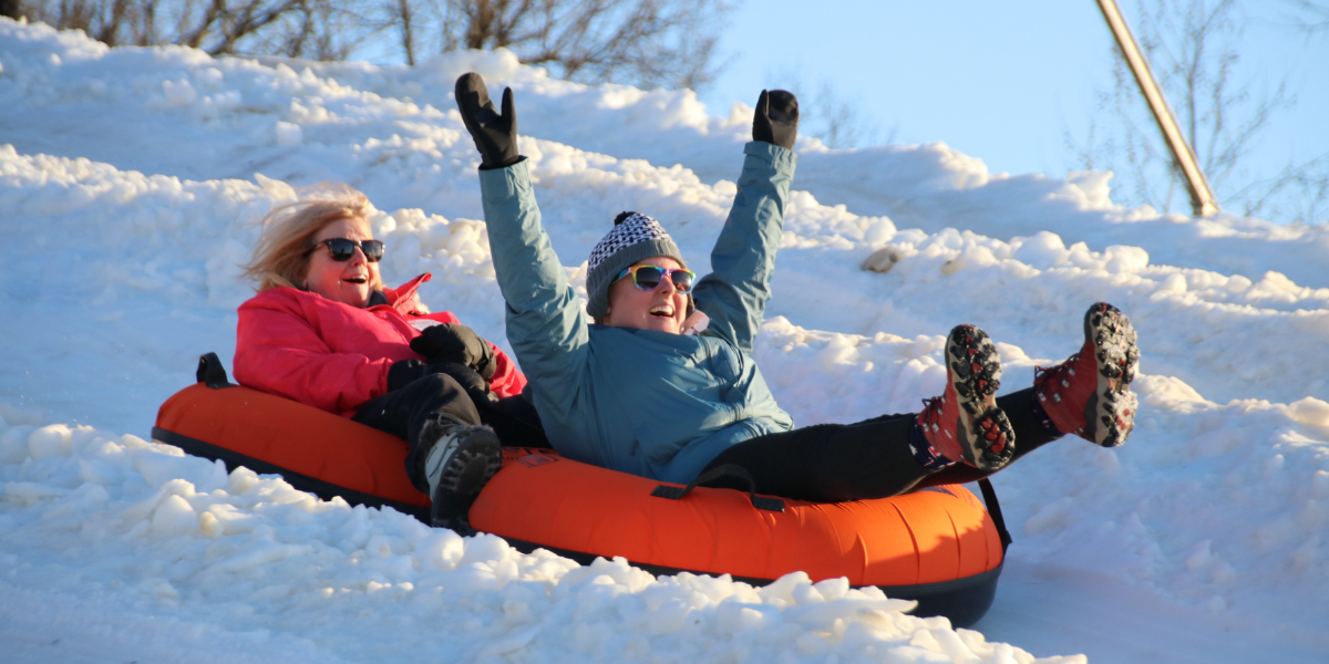 two women having fun snow tubing in west virginia